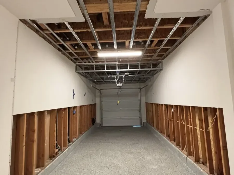 Garage walls with drywall flood cuts along both sides after a water heater leak