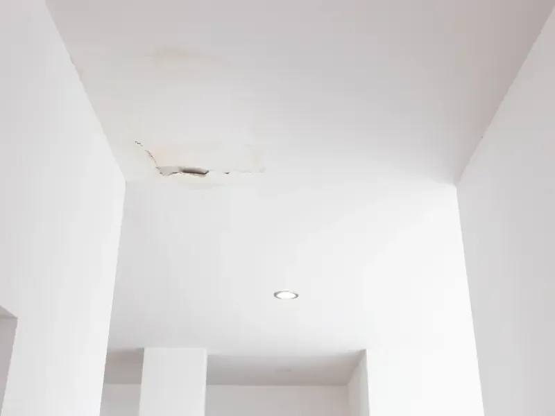 Water stains and cracked paint along a white ceiling soffit after a leak